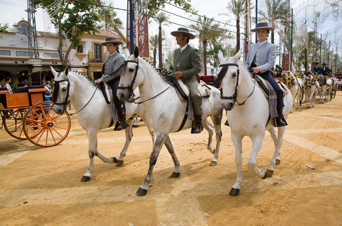 Reiter flanieren zu Pferde auf der Festmeile der Feria.